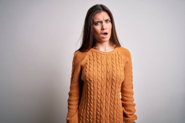 Mavi gözlü genç bir kadın beyaz arka planda sıradan bir süveter giyiyor. Şok olmuş bir yüz ifadesiyle kuşkucu ve alaycı görünüyor.