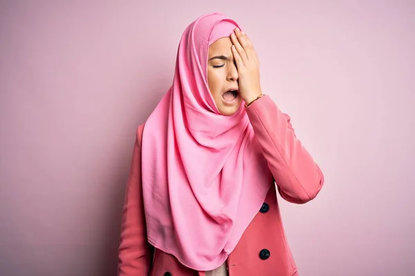 年轻美丽的女孩头戴穆斯林头巾 站在孤立的粉色背景上 用手捂住半张脸 眼睛和嘴 打呵欠累了 脸痛得厉害 — 图库照片