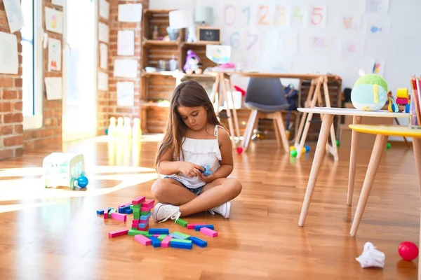 可愛い幼児が床に座っている 幼稚園の木造ブロックで遊ぶ — ストック写真
