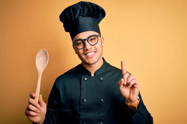 Mladý Brazilský Kuchař Uniformě Klobouku Držící Dřevěnou Lžíci Překvapený Nápadem — Stock fotografie
