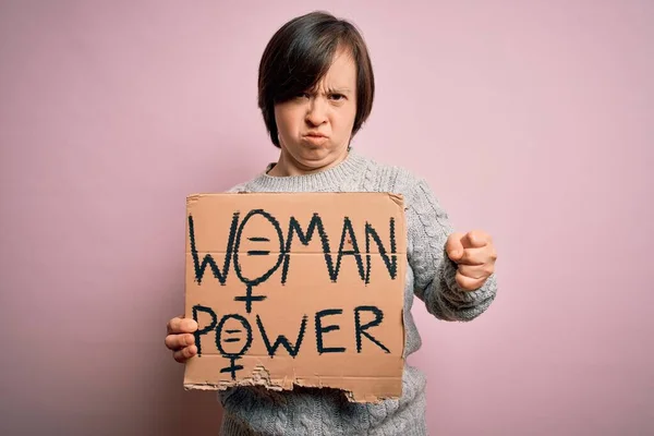 年轻的唐氏综合症妇女举着粉红背景的妇女抗议横幅 愤怒的概念使她恼怒 — 图库照片