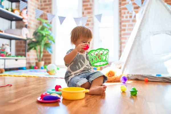 Sevimli Çocuk Yerde Oturup Kreşteki Oyuncakların Etrafında Plastik Çatal Bıçak — Stok fotoğraf