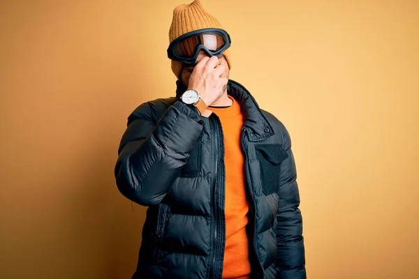 年轻英俊的滑雪者穿着雪地运动服 用滑雪护目镜擦拭疲倦的鼻子和眼睛 感觉疲劳和头痛 压力和挫败感概念 — 图库照片