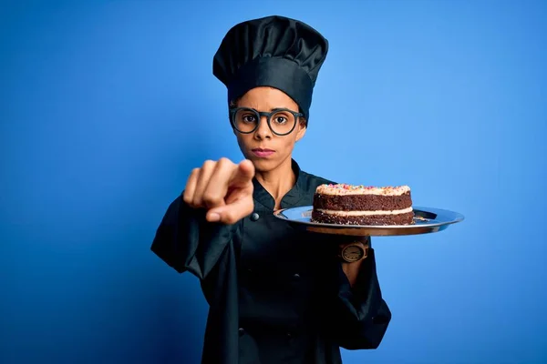 年轻的非洲裔美国面包师 身穿炊具制服 头戴帽子 手拿着蛋糕 手指着相机 对着你 正面做出积极而自信的手势 — 图库照片