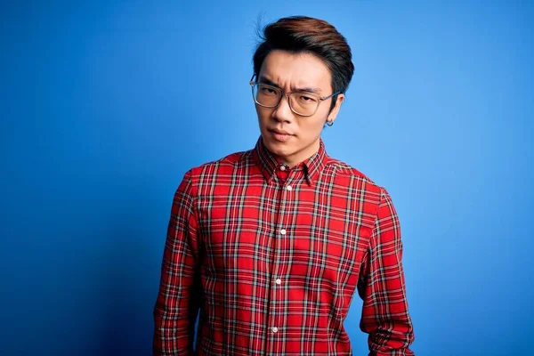 Молодой Красивый Китайский Мужчина Повседневной Рубашке Очках Синем Фоне Скептически — стоковое фото