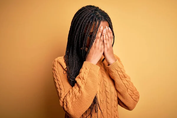 泣きながら手で顔を覆う悲しい表情で黄色の背景に眼鏡とカジュアルなセーターを身に着けている若いアフリカ系アメリカ人のスマート女性 うつ病の概念 — ストック写真