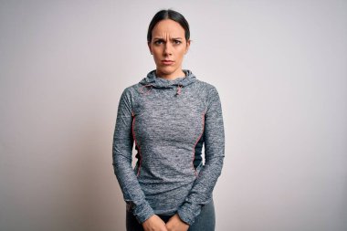 Spor kıyafetleri giyen genç sarışın fitness kadını izole edilmiş arka plan şüphecisi ve gergin, sorun yüzünden somurtuyor. Negatif kişi.