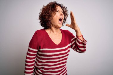 Orta yaşlı güzel kıvırcık saçlı kadın beyaz arka planda sıradan çizgili süveter giyip el ele verip bağırıyor. İletişim konsepti.
