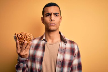 Genç, yakışıklı, Afro-Amerikalı bir adam elinde Alman krakerleriyle kaseyi tutuyor.