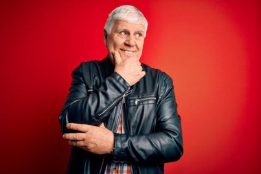 Kıdemli yakışıklı, beyaz gömlekli ve ceketli, soyutlanmış kırmızı arka planda, elleri çenesinde soru soran, düşünceli bir adam. Düşünceli bir yüzle gülümsüyor. Şüphe kavramı.