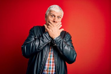 Ayrı kırmızı arka plan üzerinde gündelik gömlek ve ceket giyen kıdemli yakışıklı adam ağzını yanlışlıkla ellerle kapatarak şok etti. Gizli konsept.
