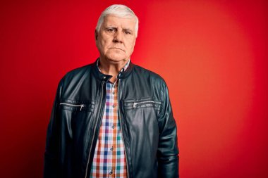 Kıdemli yakışıklı beyaz adam, izole edilmiş kırmızı arka planda günlük gömlek ve ceket giyiyor. Yüzünde ciddi bir ifadeyle rahatlamış. Basit ve doğal bir şekilde kameraya bakıyorsun..