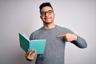 Genç, yakışıklı, zeki bir öğrenci, izole edilmiş beyaz bir arka plan üzerinde kitap okuyor.