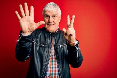 Kıdemli yakışıklı, beyaz gömlekli ve ceketli adam izole edilmiş kırmızı arka plan üzerinde yedi numaralı parmaklarıyla gülümseyerek kendinden emin ve mutlu görünüyor..