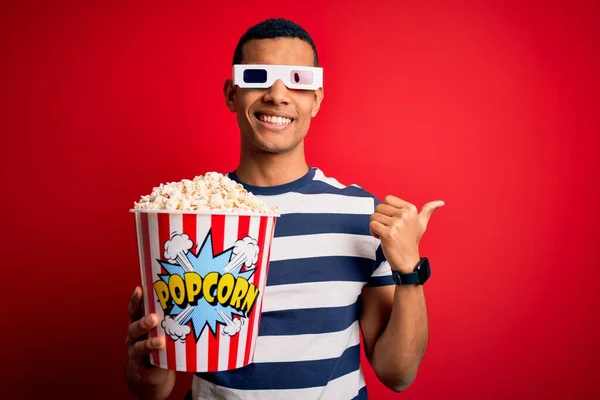 年轻英俊的非洲裔美国男人拿着3D眼镜看电影 一边吃爆米花一边举起手和大姆指 自信地微笑着 — 图库照片