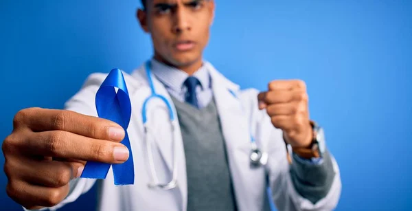 年轻英俊的非洲医生 手持蓝色癌症带符号的美国医生 生气得大叫 生气得发疯 怒气冲冲 — 图库照片