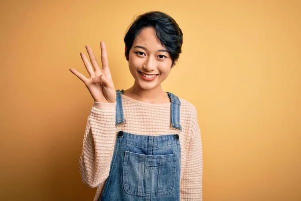 Young Beautiful Asian Girl Wearing Casual Denim Overalls Isolated Yellow — Stock Photo, Image