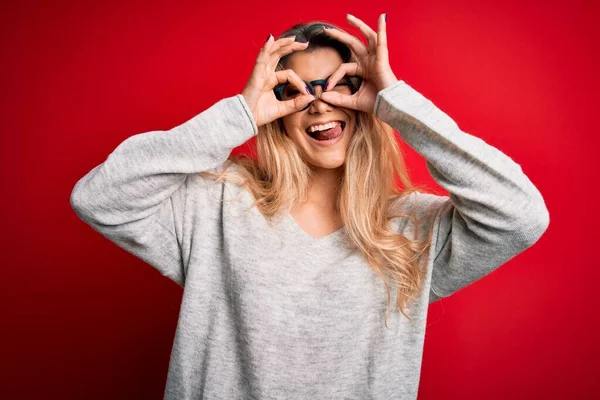 Mulher Loira Bonita Nova Vestindo Suéter Óculos Sobre Fundo Vermelho — Fotografia de Stock