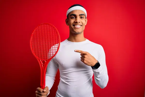 若いですハンサムなアフリカ系アメリカ人スポーツマン遊びテニス使用ラケット以上赤背景非常に幸せなポインティングとともに手と指 — ストック写真