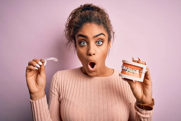 Young African American Woman Surprised Shocked Holding Professional Orthodontic Denture — Stock Photo, Image