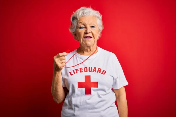 高个子漂亮的白发女救生员 身穿印有红十字会标志的T恤衫 吹口哨 脸上表情严肃 简单而自然地看着相机 — 图库照片