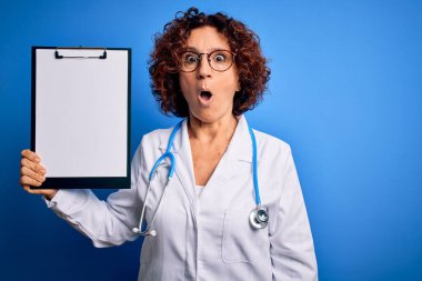 Orta yaşlı, kıvırcık saçlı, palto ve steteskop giymiş bir kadın. Elinde bir pano var. Şok geçirmiş, şaşırmış ve korku ifadesinden korkmuş.