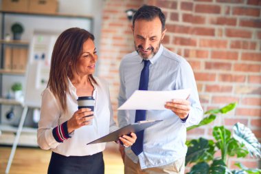 Mutlu ve kendinden emin gülümseyen iki orta yaşlı iş adamı. Yüzünde tebessümle ayakta duruyor, birlikte çalışıyor, panoyu tutuyor ve ofiste kahve içiyorduk.