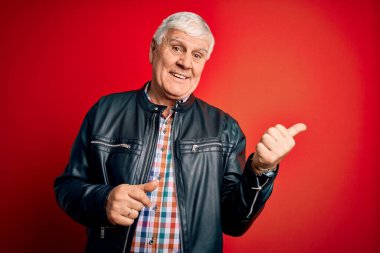 Kıdemli yakışıklı, beyaz gömlekli, ceketli, soyutlanmış, kırmızı arka planda gülümseyen, gülümseyen ve baş parmağıyla yüzünü gösteren adam..