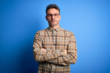 Sıradan gömlek ve gözlük takan genç yakışıklı adam mavi arka planda kuşkucu ve gergin duruyor. Yüzünde çapraz kollarla onaylamayan bir ifade var. Negatif kişi.
