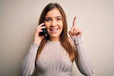 Akıllı telefondan konuşan genç bir kadın izole bir zemin üzerinde bir fikir ya da soru işareti ile şaşırmış bir şekilde mutlu bir yüz, bir numara