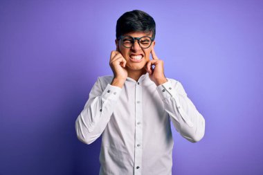 Tişört ve gözlük takan genç yakışıklı iş adamı yüksek sesli müzik sesi için kulaklarını parmaklarıyla kapatıyor. Sağır kavramı.