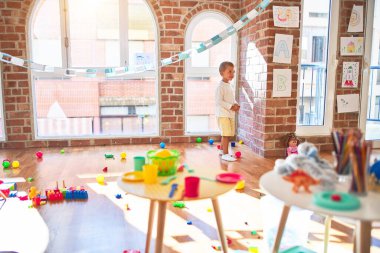 Güzel sarışın bebek mutlu gülümsüyor. Anaokulunda bir sürü oyuncağın etrafında durmak.