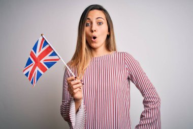 Mavi gözlü genç, sarışın bir kadın Birleşik Krallık bayrağı taşıyor. Şaşırmış bir yüzle korkmuş ve korku ifadesinden heyecanlanmış.