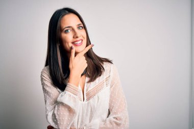 Mavi gözlü genç esmer kadın izole edilmiş beyaz arka plan üzerinde günlük tişört giyiyor kameraya bakıyor kollarını kavuşturmuş ve çenesine kaldırmış şekilde gülümsüyor. Olumlu düşünüyorum..