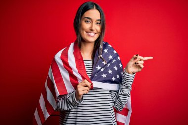 Genç, güzel, vatansever, Amerika Birleşik Devletleri bayrağı taşıyan kadın bağımsızlık gününde elini ve parmağını kenarda tutarak mutlu mesut işaret ediyor.