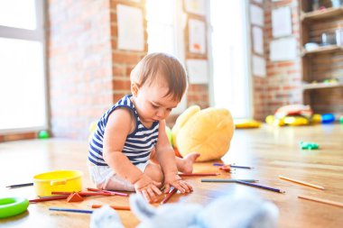Anaokulunda bir sürü oyuncakla oynayan sevimli bir çocuk.