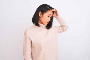 Balıkçı yaka kazak giyen genç bir kadın izole edilmiş beyaz arka planda duruyor. Alnındaki sorun yüzünden endişeli ve stresli. Kriz konusunda endişeli.