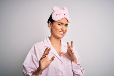 Genç, esmer, güzel bir kadın, beyaz arka planda pijama ve uyku maskesi takıyor. İğrenç bir ifade takınıyor ve tiksinti reaksiyonu yüzünden tiksiniyor. Eller havada