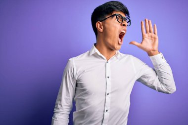 Mor arka planda gömlek ve gözlük takmış genç yakışıklı iş adamı el ele tutuşarak bağırıyor ve çığlık çığlığa bağırıyordu. İletişim konsepti.