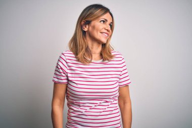 Orta yaşlı güzel bir kadın izole edilmiş beyaz arka plan üzerine sıradan çizgili tişört giyip yüzünde gülümsemeyle, doğal bir ifadeyle yan yana bakıyor. Kendinden emin gülen.