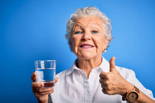 Senior Bela Mulher Beber Copo Água Sobre Fundo Azul Isolado — Fotografia de Stock