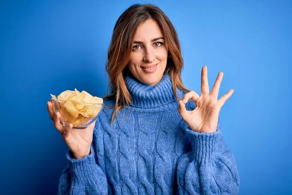 Young Beautiful Brunette Woman Holding Bowl Potato Chips Blue Background — Stock Photo, Image