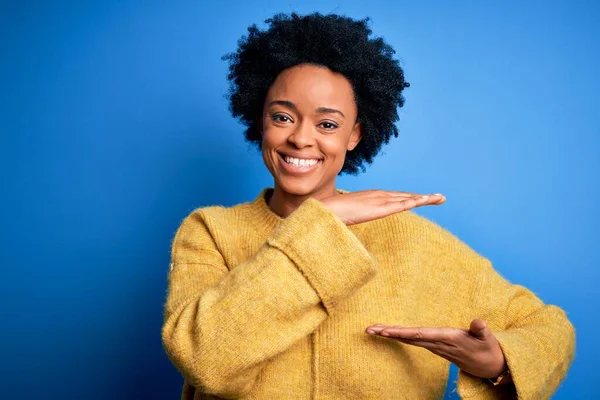 手でジェスチャーを黄色のカジュアルなセーターを着て巻き毛を持つ若い美しいアフリカ系アメリカ人アフロ女性は 大小のサインを示す 指標シンボル カメラを見て微笑んだ 概念の測定 — ストック写真
