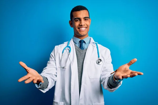 英俊的非洲裔美国医生 身穿外套 带着听诊器 头戴蓝色背景的男子 笑容满面 伸出援手 给予帮助和接纳 — 图库照片