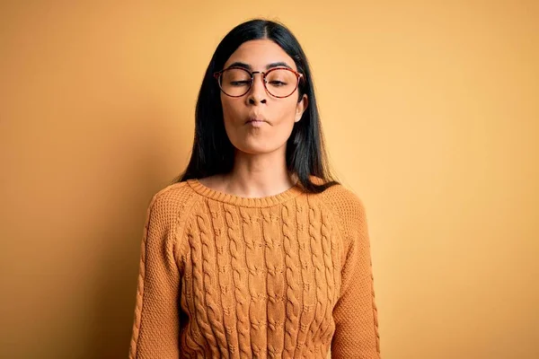 狂気とコミカルなジェスチャーで魚の顔を作る黄色の孤立した背景に眼鏡をかけて若い美しいヒスパニック系の女性 面白い表現 — ストック写真