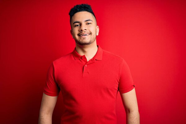 Young handsome man wearing red casual polo standing over isolated background with a happy and cool smile on face. Lucky person.