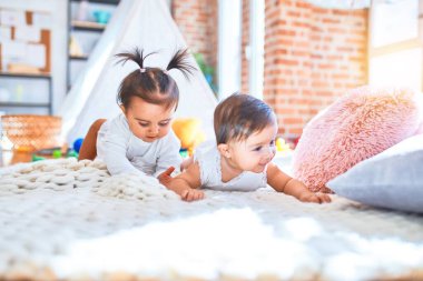 Güzel bebek mutlu kızlar evde birlikte oynuyorlar battaniyenin üzerinde uzanarak.