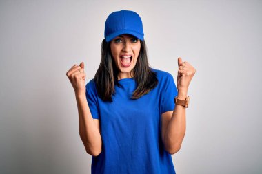 Mavi arka planda duran mavi gözlü genç teslimatçı kadın kollarını kaldırarak ve açık gözlerle başarıyı kutluyor ve şaşırıyor. Kazanan konsept.