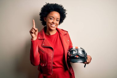 Kıvırcık saçlı, motosiklet kaskı tutan, başarılı bir fikri olan Afro-Amerikan motosikletli genç bir kadın. Heyecanlı ve mutlu. Bir numara..