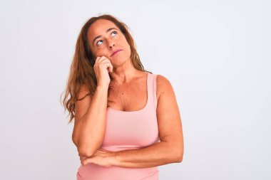 Orta yaşlı olgun bir kadın, beyaz soyutlanmış arka planda, elleri çenesinde soru sorarken, düşünceli bir ifade takınıyor. Düşünceli bir yüzle gülümsüyor. Şüphe kavramı.